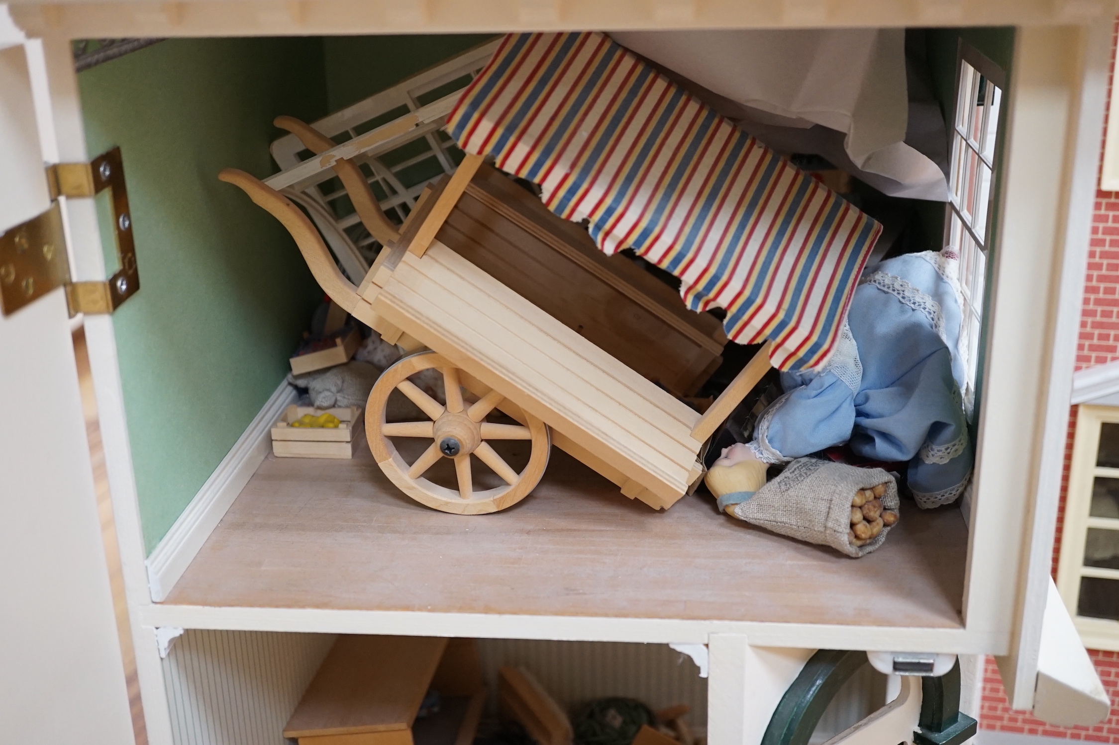 A modern Georgian style dolls house, with two front opening doors, containing six rooms with furnishings, figures, and electric lighting, together with a dolls shop, containing two rooms, furnishings, and accessories, et